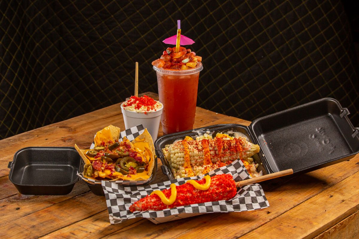 Assorted Mexican street food including corn and nachos on a wooden table