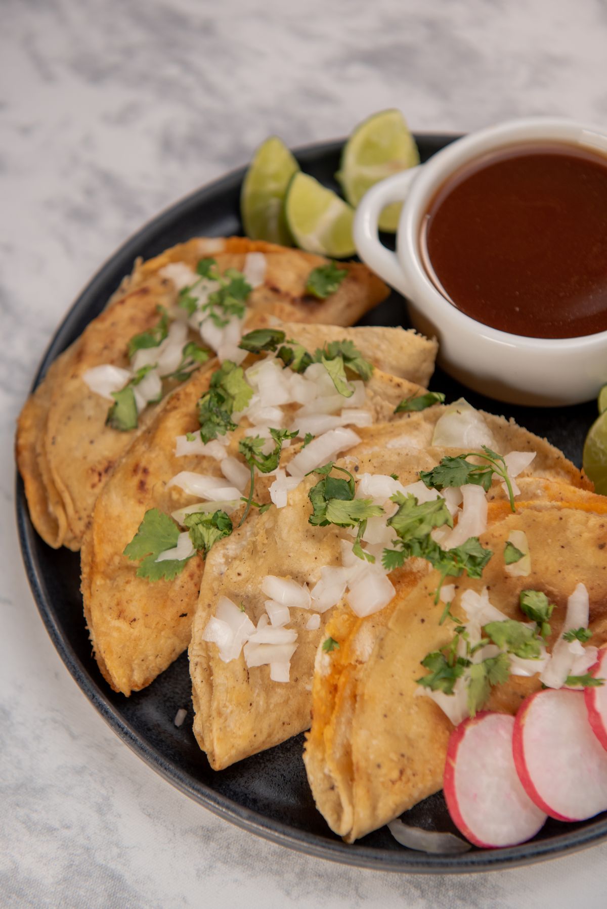 Plate of classic street tacos topped with cilantro and onion