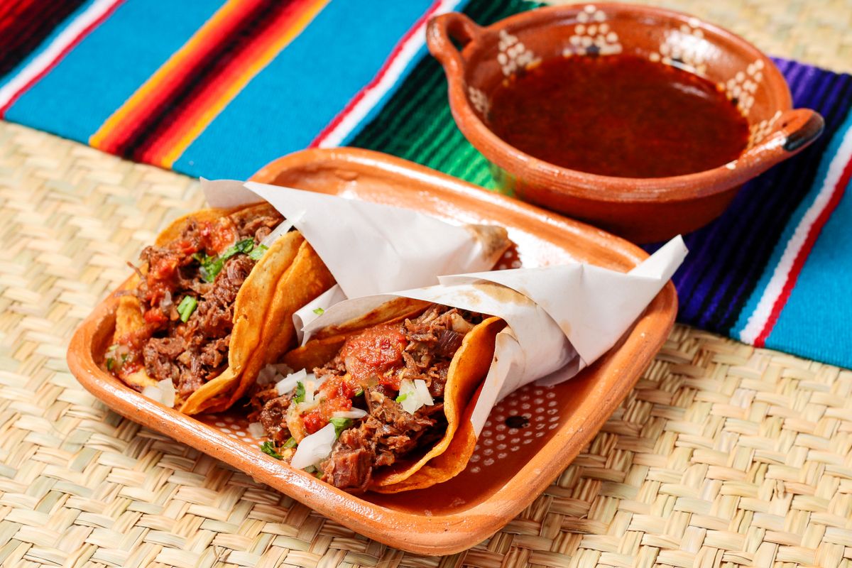 Tray of tacos filled with savory meat and salsa